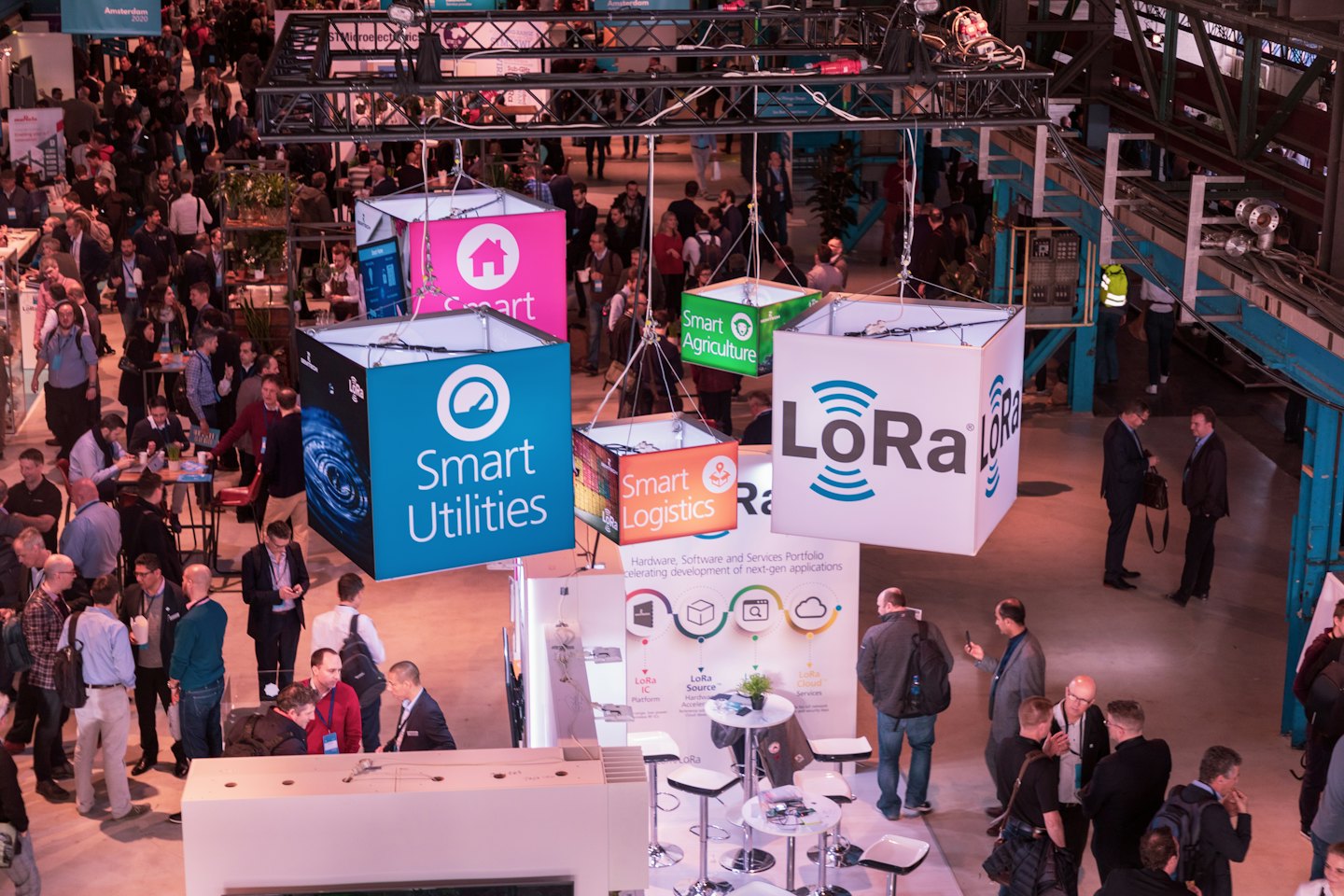 Attendees walk between exhibition booths at a busy technology conference.