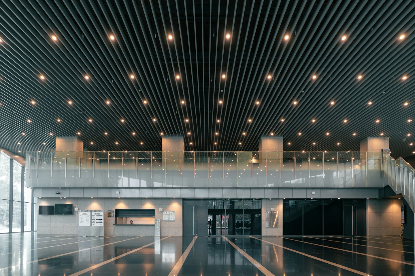 Modern office lobby with a slatted ceiling and reception desk.