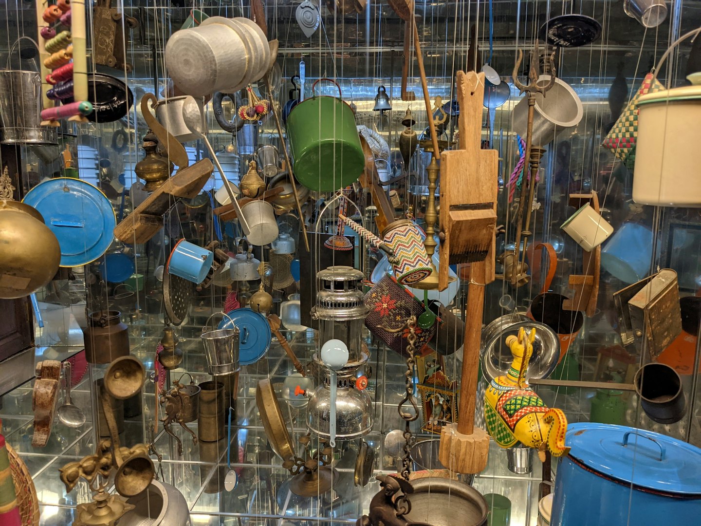 Traditional kitchen tools and metal vessels hang from wires.
