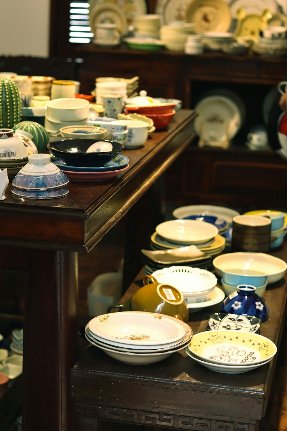 Colorful ceramic plates and cups arranged on wooden store shelves.