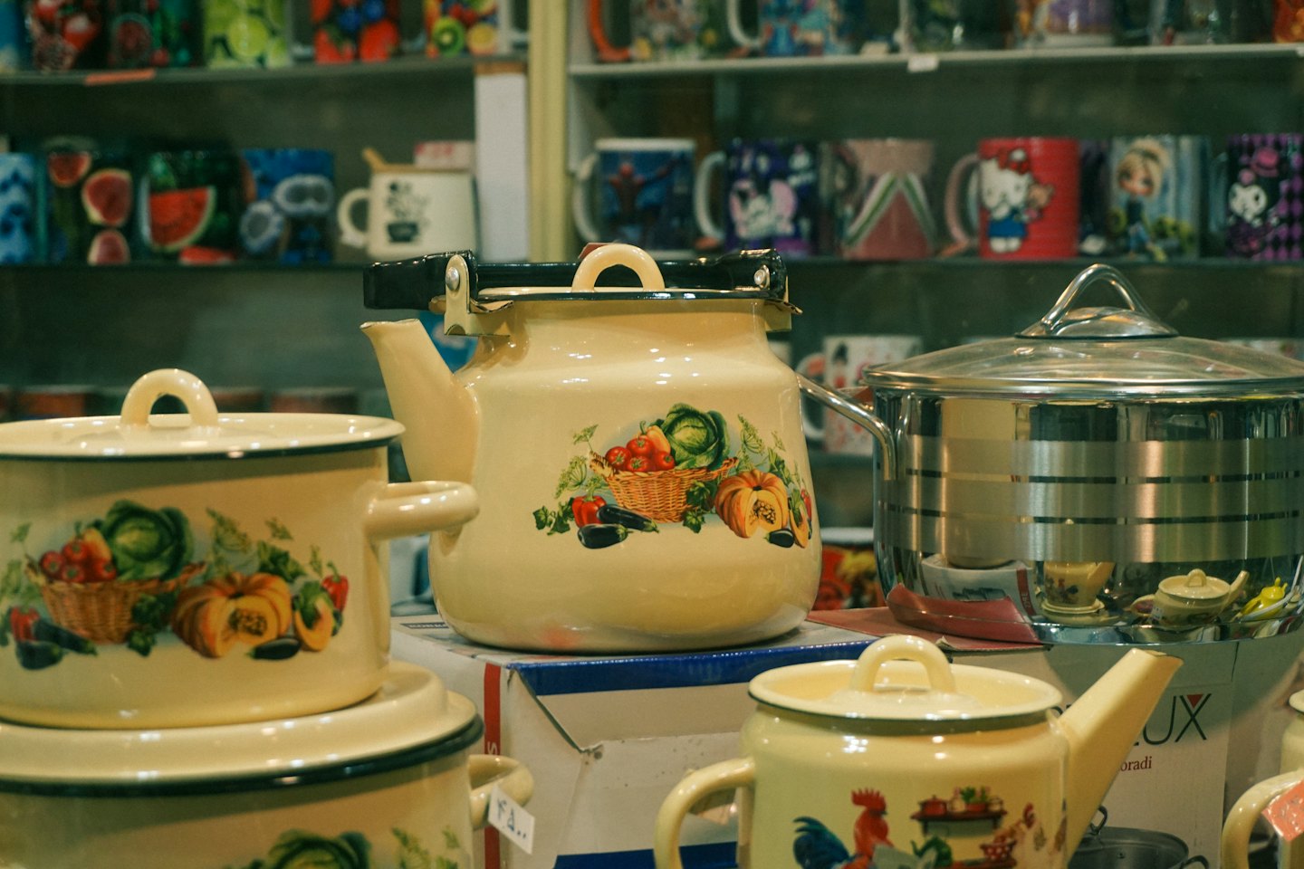 Enameled pots and stainless steel cookware displayed on retail shelves.