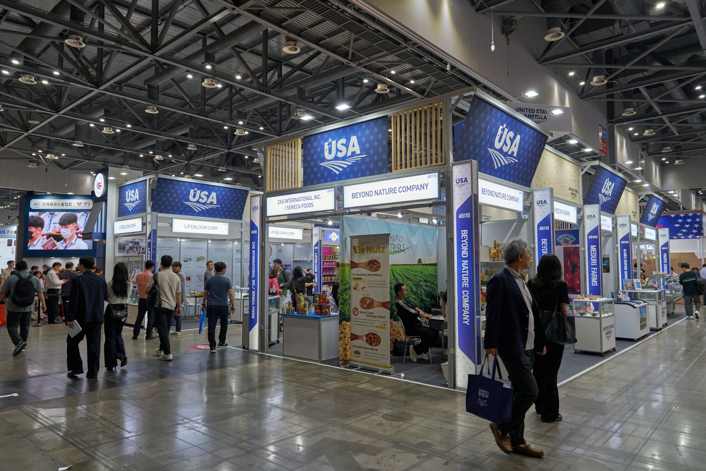 Business professionals network between exhibition booths at a trade show.