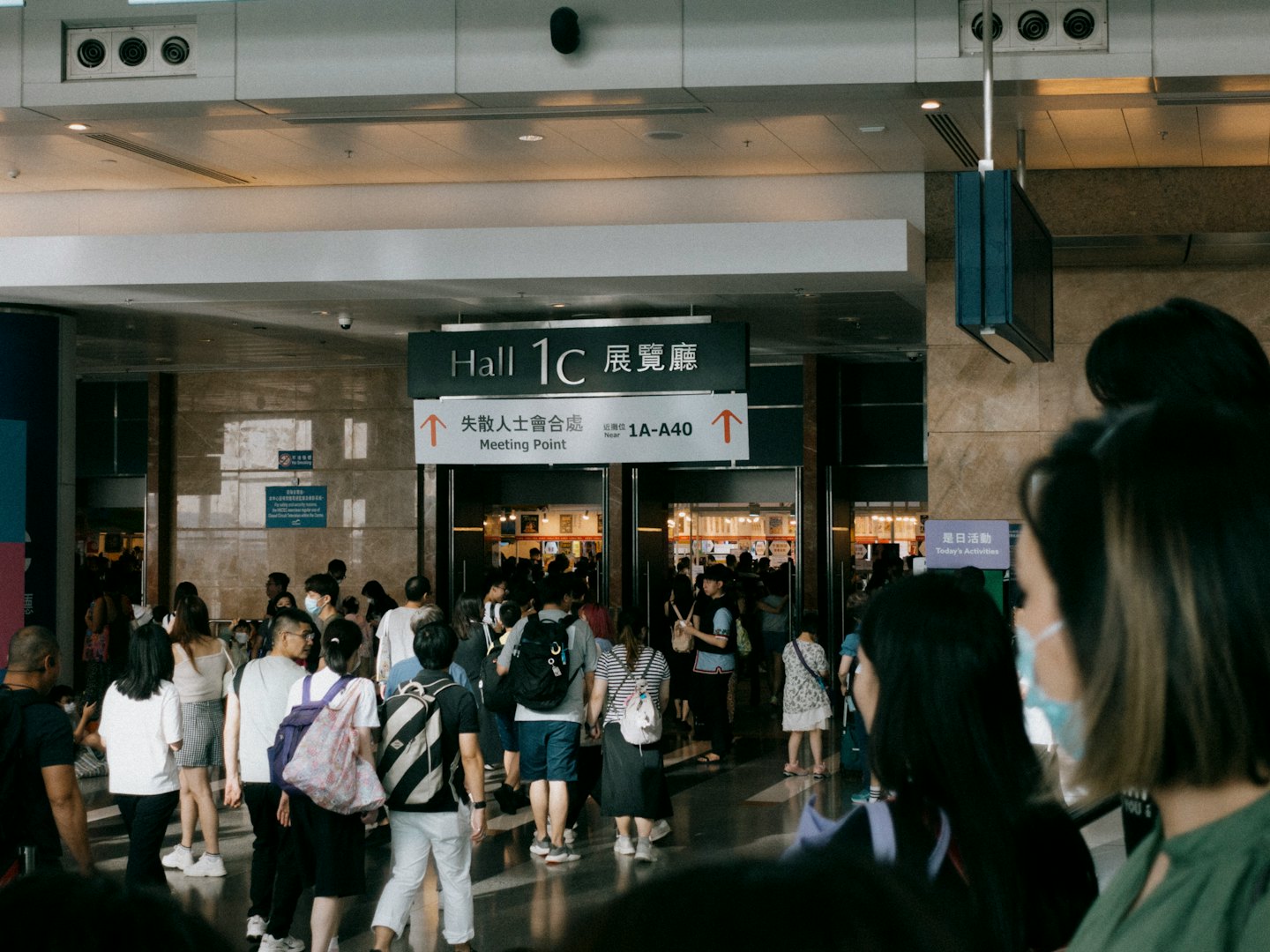 Crowd of people walking toward the exhibition hall entrance.