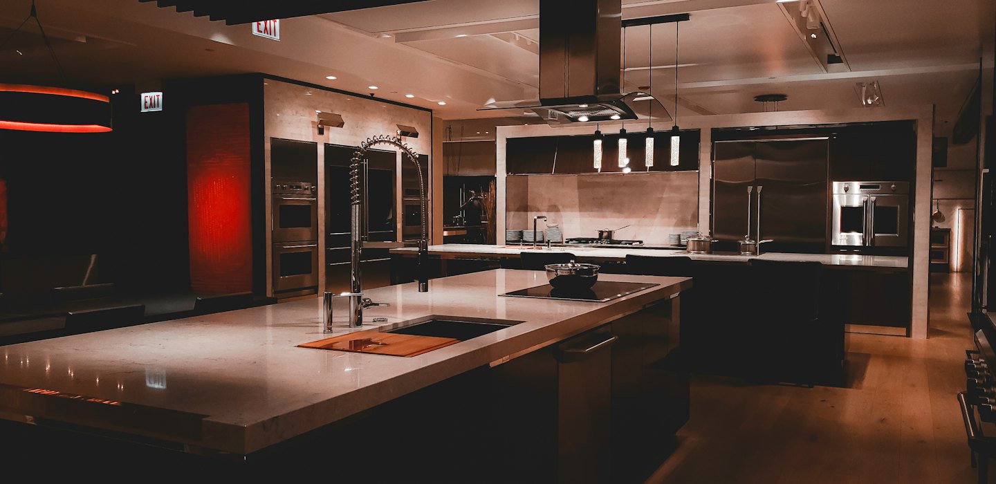 Modern kitchen showroom featuring two islands and stainless steel appliances.