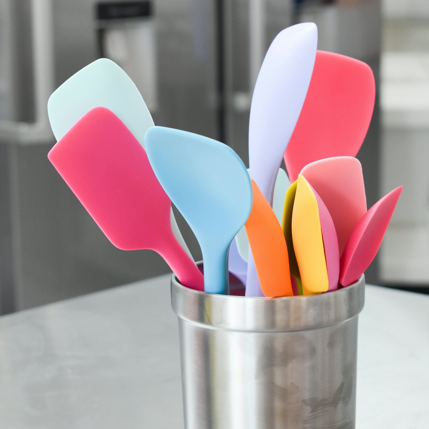 Colorful silicone kitchen utensils organized in a stainless steel holder.