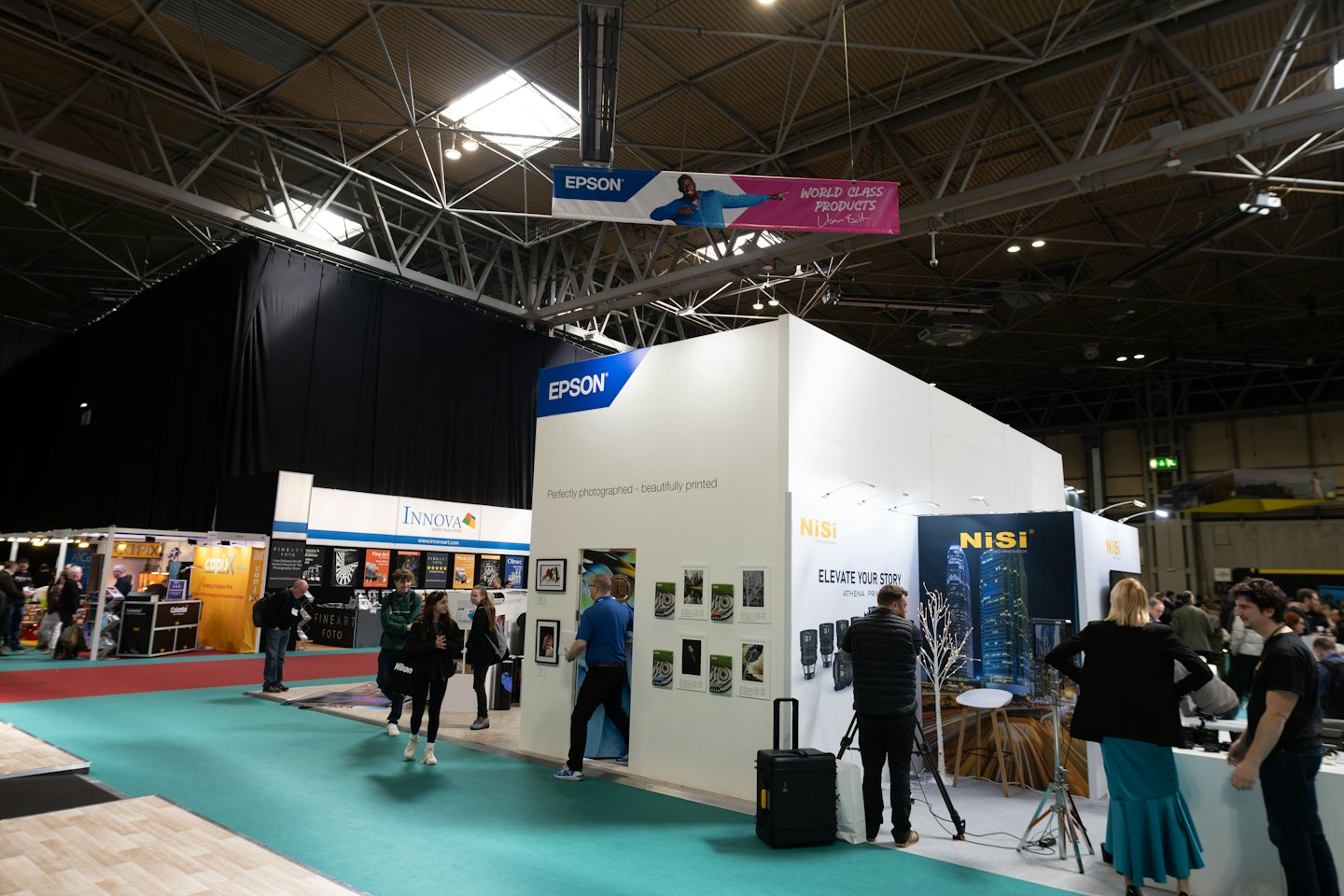 Attendees walk among branded booths on a busy trade show floor.